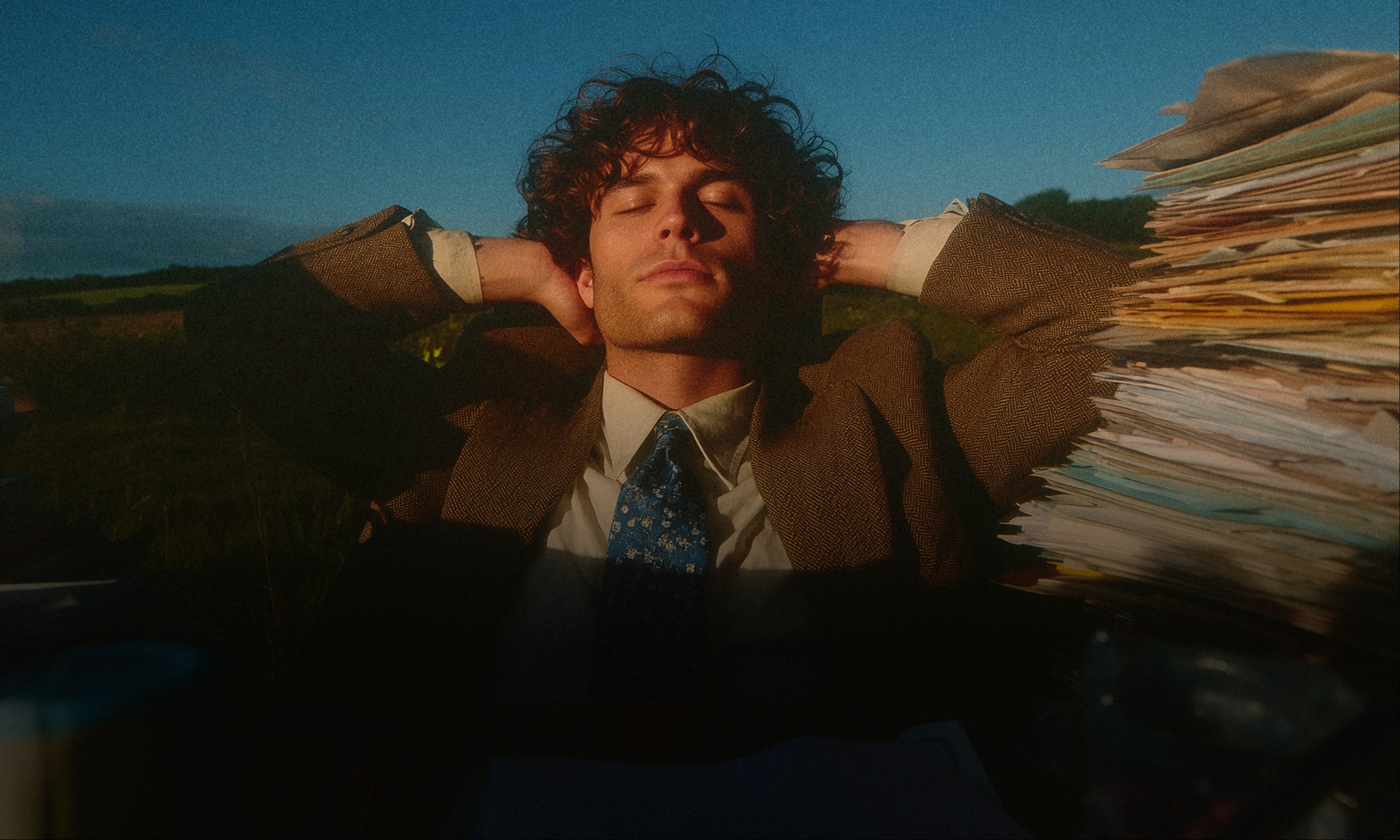 Person relaxing outdoors next to a large stack of paperwork — illustrating how Wooma property inventory software removes the admin burden
