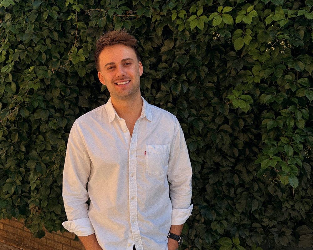 Fraser Mair, Founder at Wooma, smiling outdoors in front of a green hedge